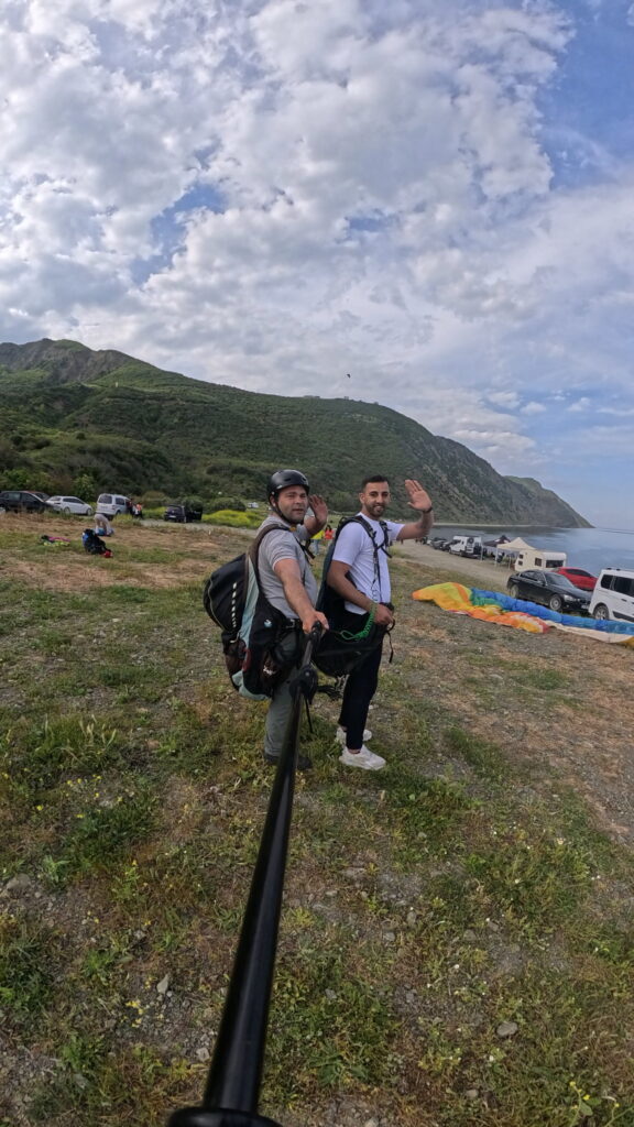 Uçmakdere'de yamaç paraşütü yapan iki kişi, deniz ve doğa manzarasıyla birlikte.