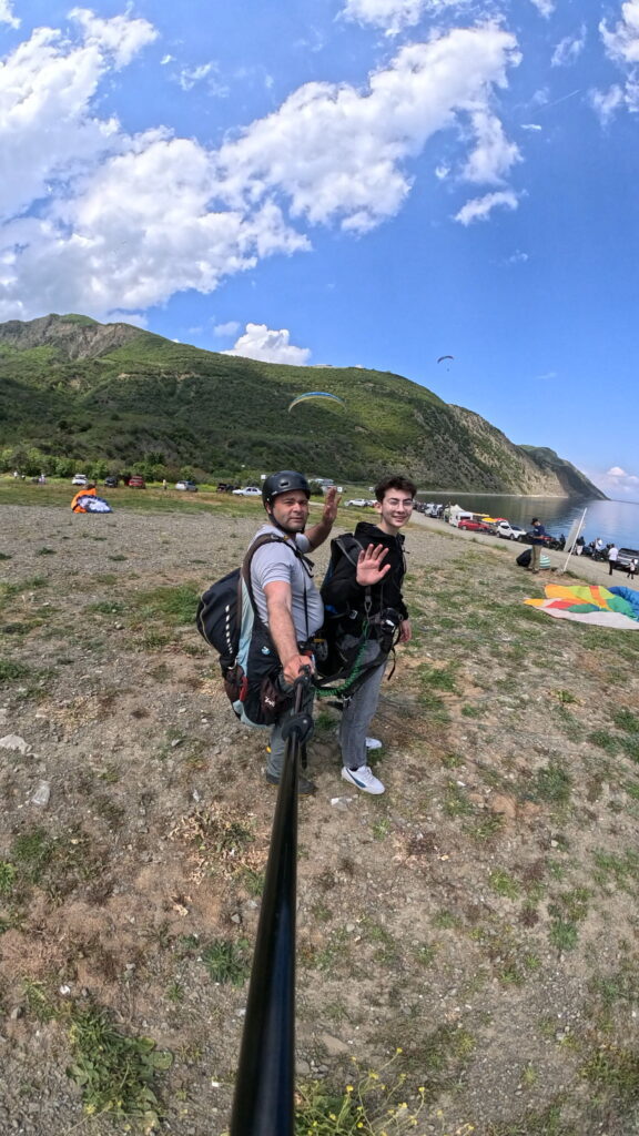 Uçmakdere'de yamaç paraşütü yapan iki kişi, güzel doğa ve deniz manzarası eşliğinde heyecan dolu anl.